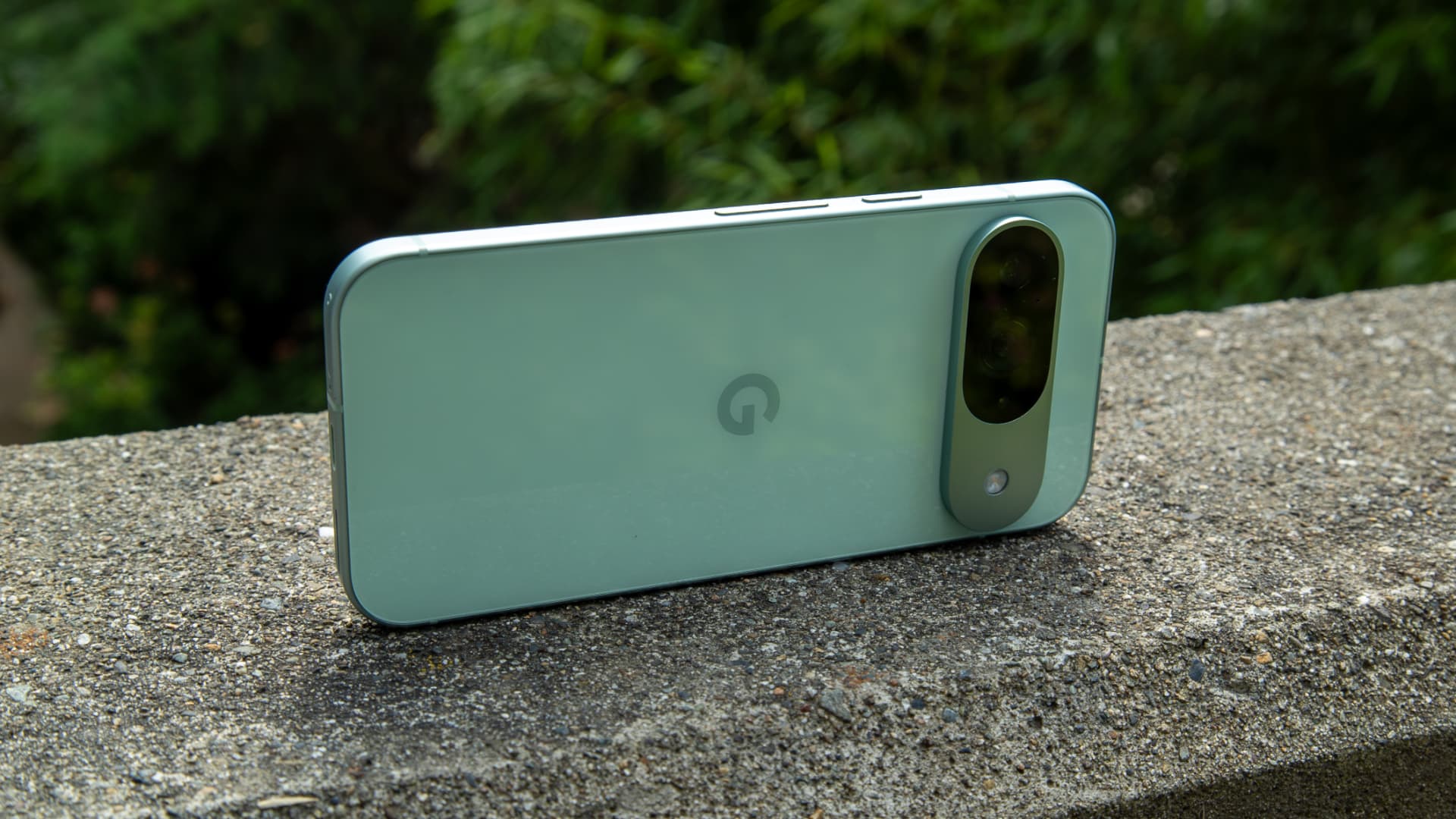 Green Pixel-style smartphone resting outdoors on a stone surface